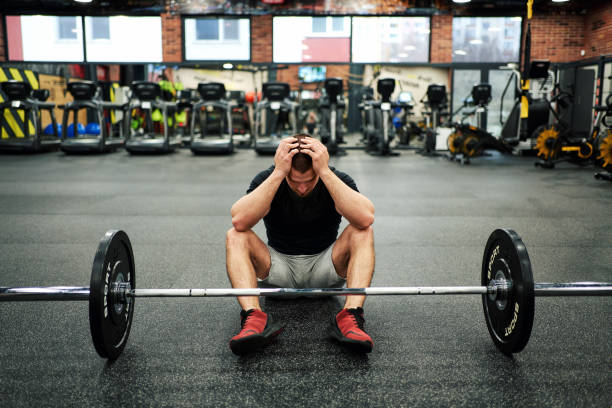 übertraining. männlicher sportler mit kopfschmerzen während des arbeitsabschlusses - body building men flexing muscles male stock-fotos und bilder