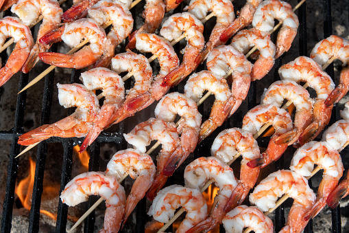 Close image of jumbo shrimp being prepared on a fiery grill.