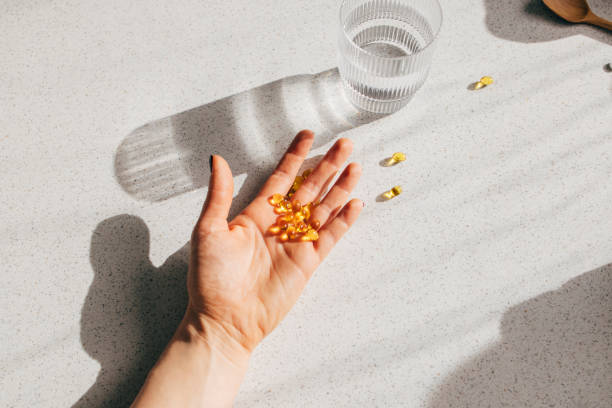 Overhead Shot of an Anonymous Person's Hand Holding Vitamin D Pills A high angle shot of an unrecognizable person's hand holding a bunch of vitamin D pills. vitamin d stock pictures, royalty-free photos & images