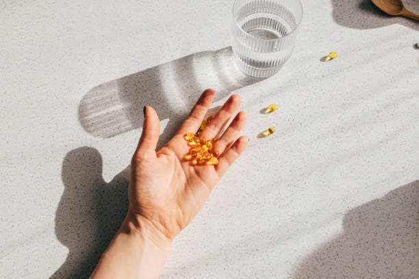 overhead shot of an anonymous person's hand holding vitamin d pills - nutritional supplement fotos imagens e fotografias de stock