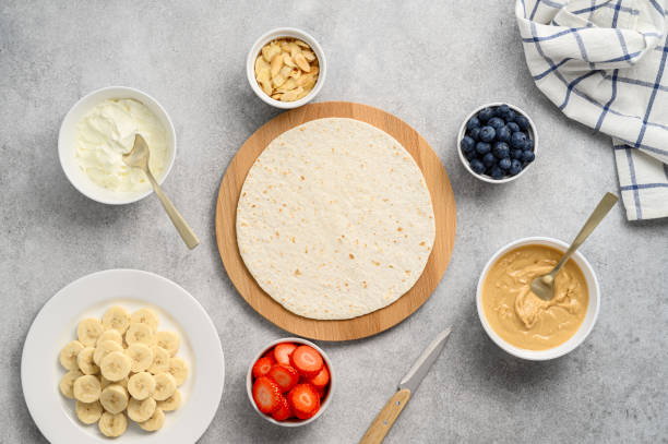 Tortilla cooking process with different fillings of peanut butter, banana, strawberry, blueberry, almond. Food trend stock photo