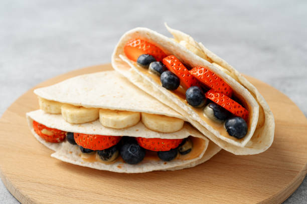 Tortilla cooking with different fillings of peanut butter, banana, strawberry, blueberry, almond. Food trend stock photo