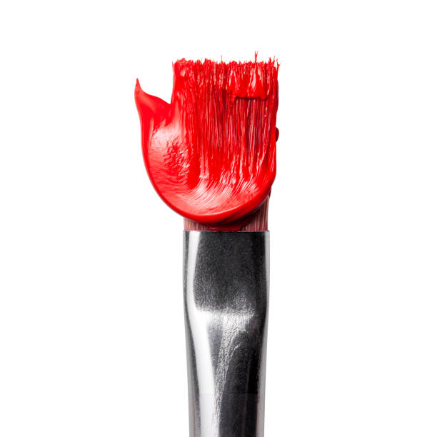 top view of several paint brushes with bright drops of yellow, red, and blue paint on the tips against a soft white background with copy space for banner design