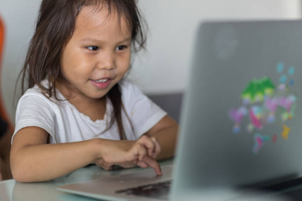 istock Happy little girl using a laptop computer at home. 1306362365