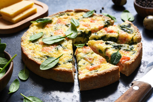 istock Tart with salmon and spinach, cheese on a black concrete background. Quiche with fish. 1306363177