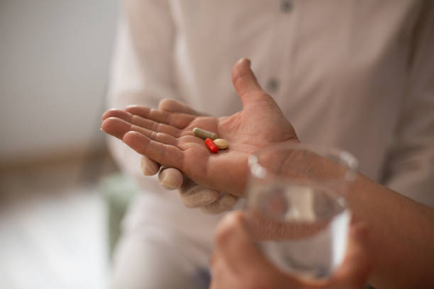 istock Patient taking pills with glass of water. Selective focus. Close-up. 1306367454
