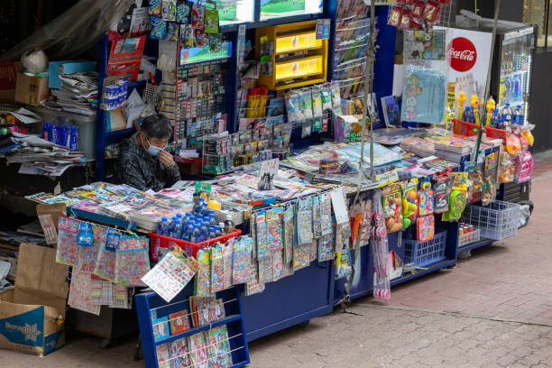 News stand in Causeway Bay, Hong Kong Hong Kong - March 10, 2021 : News vendor wearing face masks at the news stand in Causeway Bay, Hong Kong. Many newspapers, magazines, books and cigarettes are on sell at the news stand. newspaper seller stock pictures, royalty-free photos & images