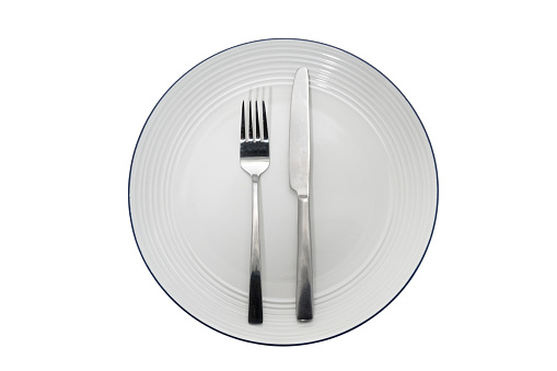 Empty round dinner plate with a knife and fork - white background