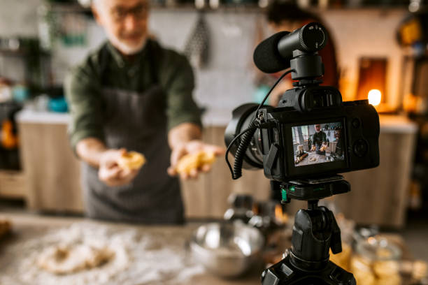 Senior vlogger broadcasting live cooking video online Senior Food Vlogger live streaming. Recording his podcast internet show, talking about pasta and italian food. cooking show stock pictures, royalty-free photos & images