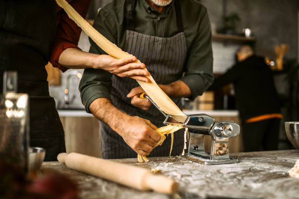 istock Cutting pasta dough into fettuccine using the manual pasta maker 1306372375
