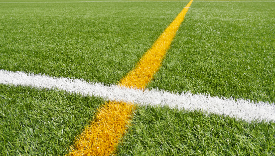 Close-up of artificial turf at the athletics stadium, drawn white and yellow lines