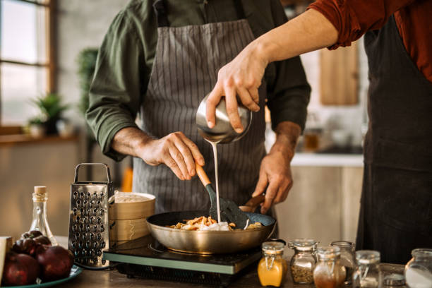 Young man learning cooking skills from an experienced chef.