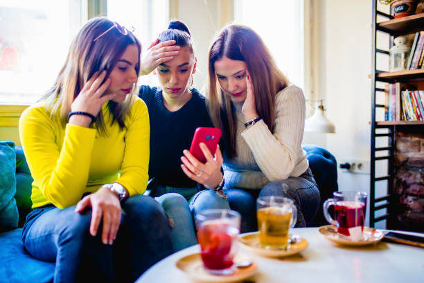 istock Shocked young women using mobile phone in a cafe 1306372750