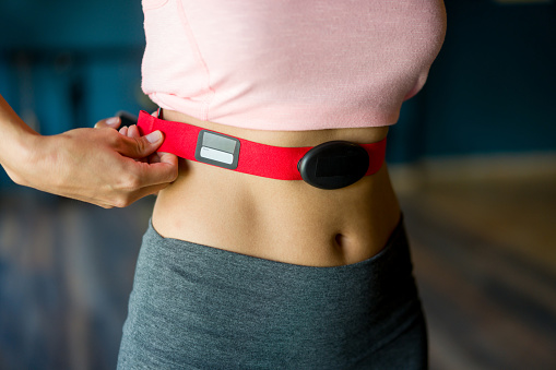Close-up on a woman at the gym putting on a fitness tracker to monitor her calories and heart rate - fitness goals concepts
