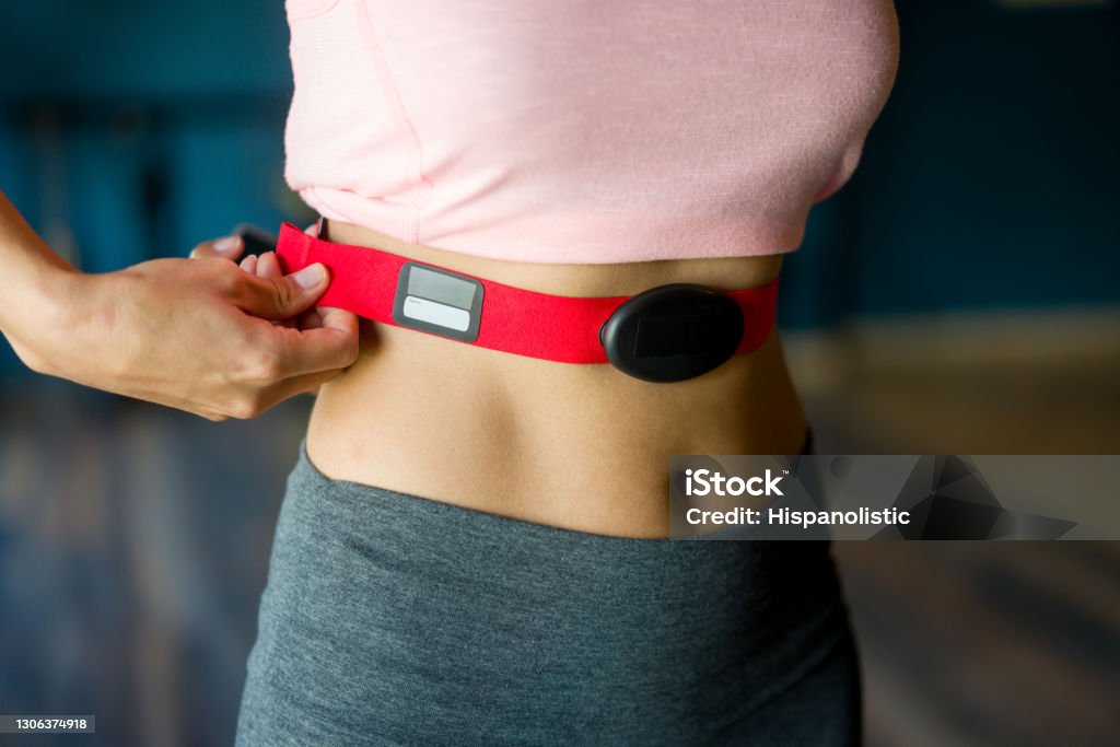 Close-up on a woman at the gym putting on a fitness tracker Close-up on a woman at the gym putting on a fitness tracker to monitor her calories and heart rate - fitness goals concepts Electrocardiography Stock Photo