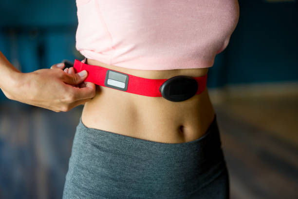 Close-up on a woman at the gym putting on a fitness tracker Close-up on a woman at the gym putting on a fitness tracker to monitor her calories and heart rate - fitness goals concepts strap photos stock pictures, royalty-free photos & images