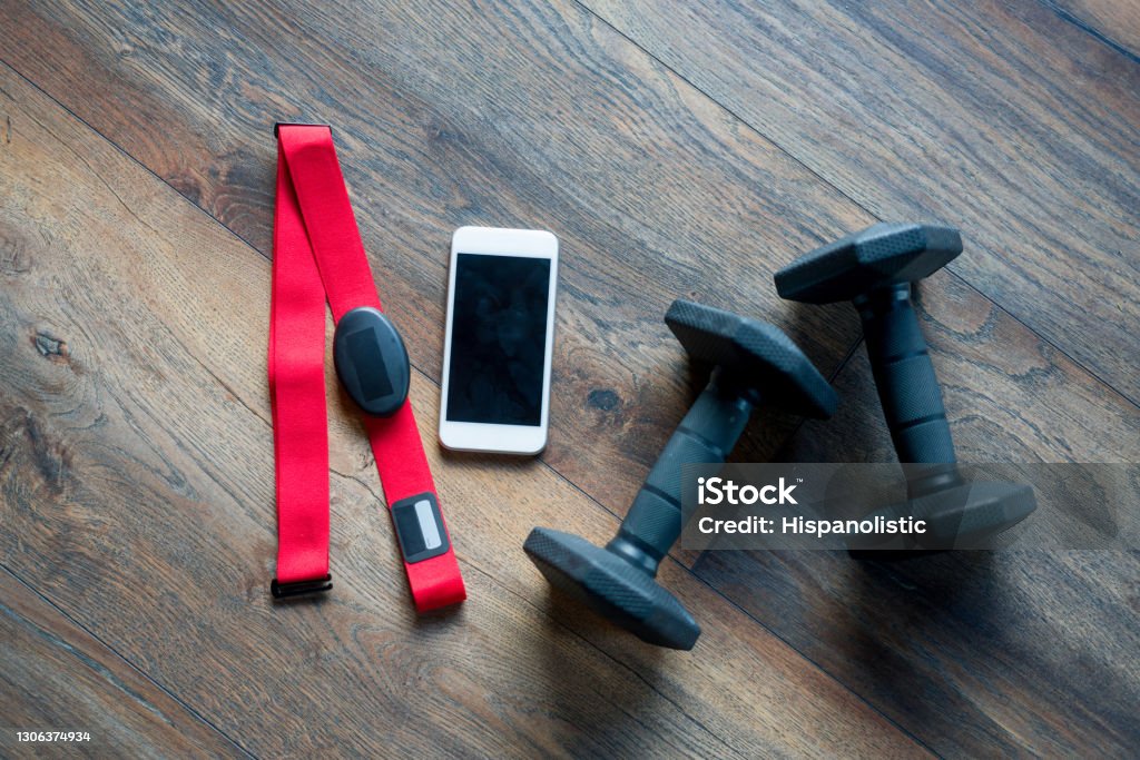 Fitness equipment for a good workout Fitness equipment for a good workout lying on the floor at the gym - fitness tracker and weights Mobile App Stock Photo
