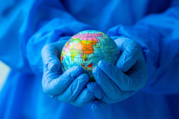 istock women wearing PPE suit holding glass globe 1306377586