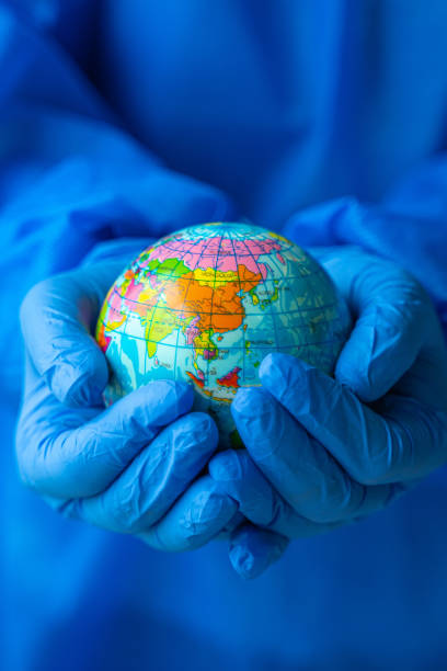 istock women wearing PPE suit holding glass globe 1306377592