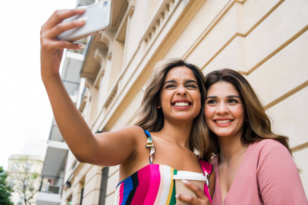istock Two friends taking selfie with phone outdoors. 1306377689
