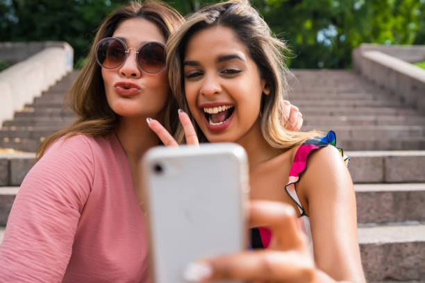 istock Two friends taking selfie with phone outdoors. 1306377695