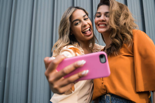 istock Two friends taking selfie with phone outdoors. 1306377715