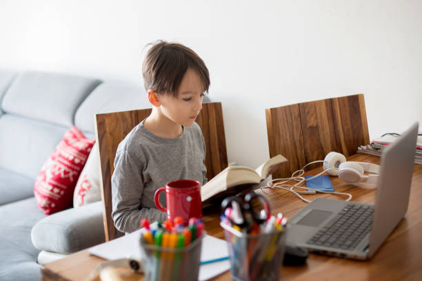 istock School child, sitting at the table with laptop, writing school tasks while homeschooling 1306382317