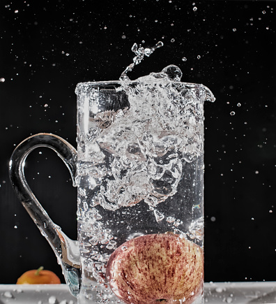 Close up of an apple falling into water and splashing