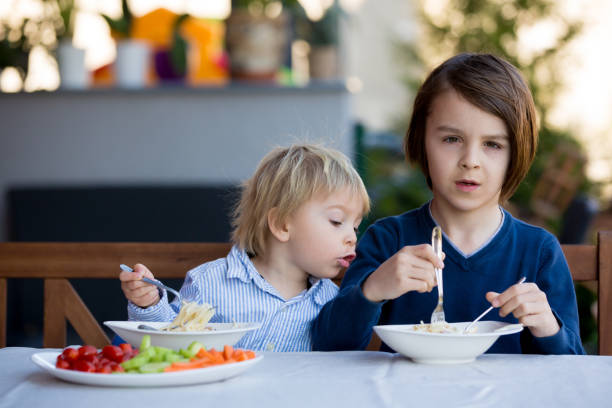 istock Cute children, boy brothers, eating spaghetti in garden 1306386521