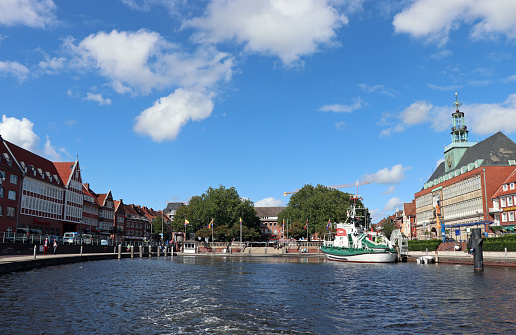 Emden, Germany - September 05, 2020: City hall in the center of Emden. In the foreground you can see the rescue cruiser 'Georg Breusing', which has been a floating museum in the Emder Ratsdelft since 1988.