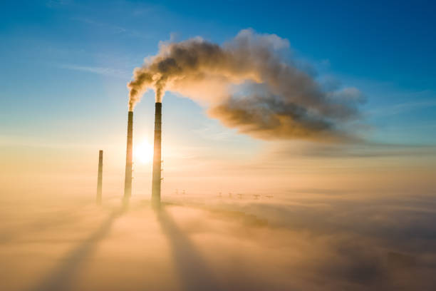 Aerial view of coal power plant high pipes with black smoke moving up polluting atmosphere at sunset. Aerial view of coal power plant high pipes with black smoke moving up polluting atmosphere at sunset. smoke stack photos stock pictures, royalty-free photos & images