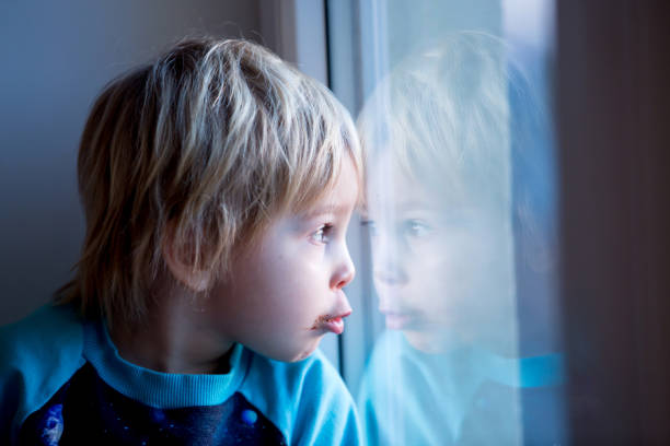 istock Toddler child, sitting on the window on sunset 1306389589