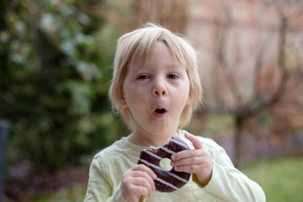 istock Sweet toddler child, playing with chocolate donuts, eating them 1306392959