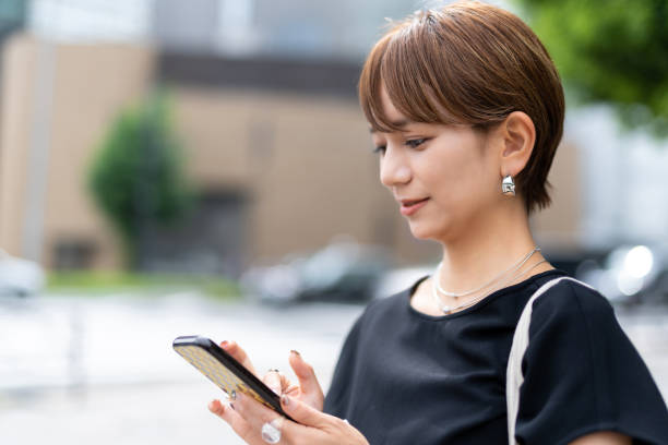 mulher asiática usando telefone inteligente, lá fora. - rush hour commuter on the phone tokyo prefecture - fotografias e filmes do acervo