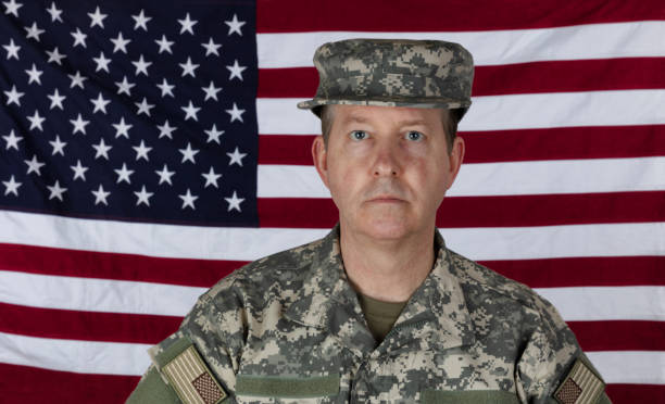 istock Man wearing military outer shirt plus cap with US flag in background 1306394736