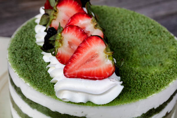 Overhead view of green tea cake with sliced strawberries on top