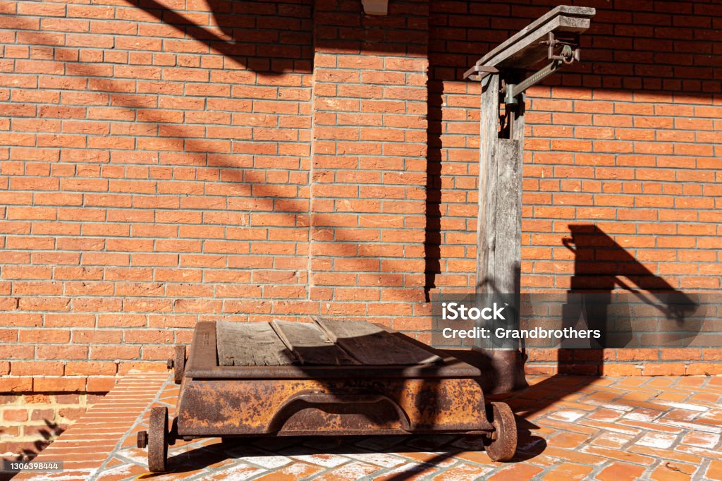 A vintage rusty industrial size platform scale with metal wheels and a beam balance A vintage rusty industrial size platform scale with metal wheels and a beam balance. This antique item is on display on the platform of historic 19th century railway station in Rockville, Maryland. Railroad Station Platform Stock Photo