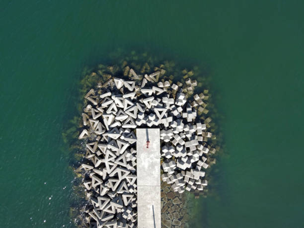 Aerial view of breakwater with concrete blocks Aerial view of breakwater with concrete blocks, white jetty against deep green water groyne stock pictures, royalty-free photos & images