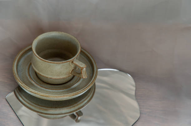 istock Handmade ceramic coffee mug  on mirror on fabric textured table cloth. 1306401096