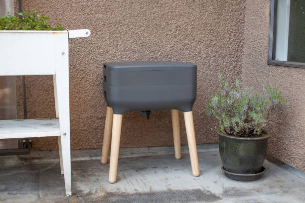 A vermicomposting system (worm composter) sits on an apartment balcony with other patio planters. A vermicomposting system (worm composter) sits on an apartment balcony with other patio planters. Worms eat food scraps and produce worm castings and worm tea to be used as fertilizer eisenia fetida stock pictures, royalty-free photos & images