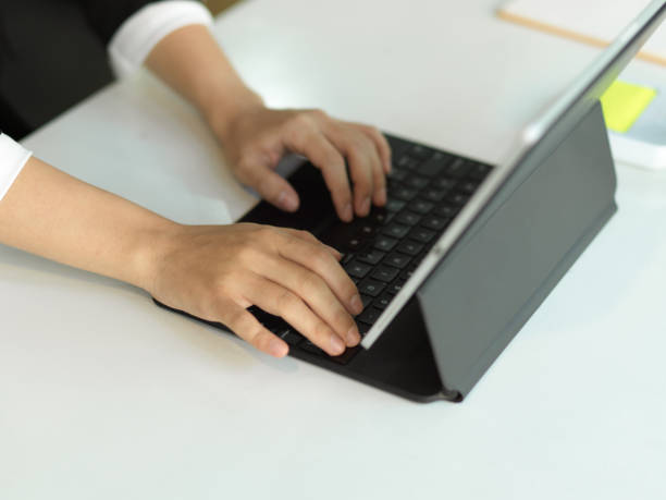 istock Female office worker hands typing on tablet keyboard on white table in office room 1306411969