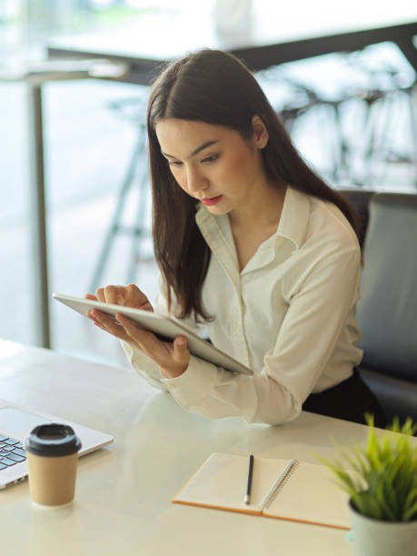 istock Busy female office worker concentrating on her work with digital tablet in her hand 1306411978
