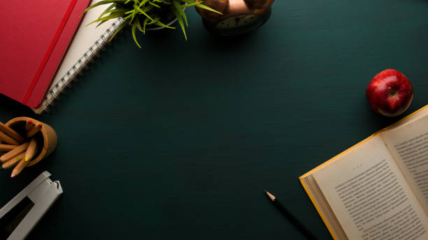 istock Study table with book, stationery, notebook, supplies and copy space on dark green table, school elements 1306412010