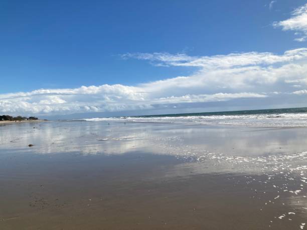 istock White clouds reflect on wet sand on a beautiful sunny day 1306412855
