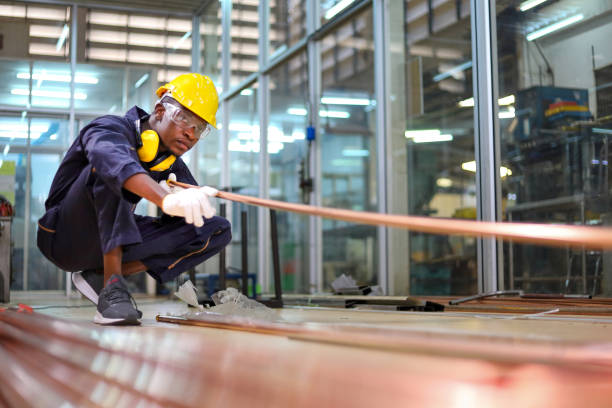African American mechanic engineer worker is choosing copper tube for sawing while working in coolant factory