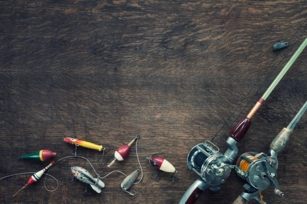 Vintage Fishing Tackle Background Vintage fishing rod, reel, line, lantern and lures/tackle on an old wood background fishing tackle old fashioned antique fishing hook stock pictures, royalty-free photos & images