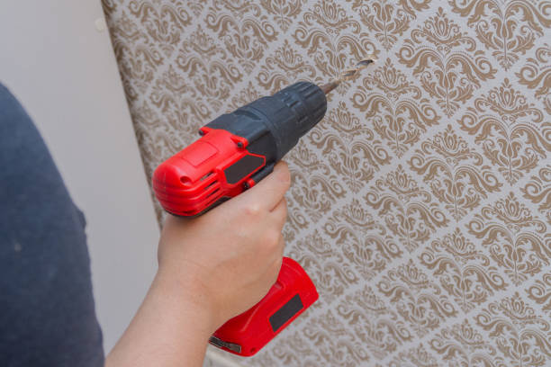 white woman sticking a wall with arabesque wallpaper with a red drill in her hand white woman sticking a wall with arabesque wallpaper with a red drill in her hand in Rio de Janeiro. arabesco stock pictures, royalty-free photos & images