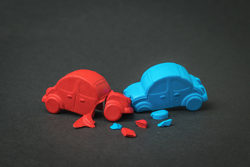 Installation of a car accident between a red and blue car on a black background. A traffic accident.