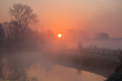 Early on a frosty morning with fog rising along a river with several bends