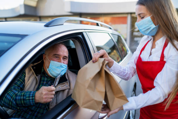 istock Order Being Passed Between  Hands Through Car Window Outside Restaurant During Covid-19 Lockdown 1306425148